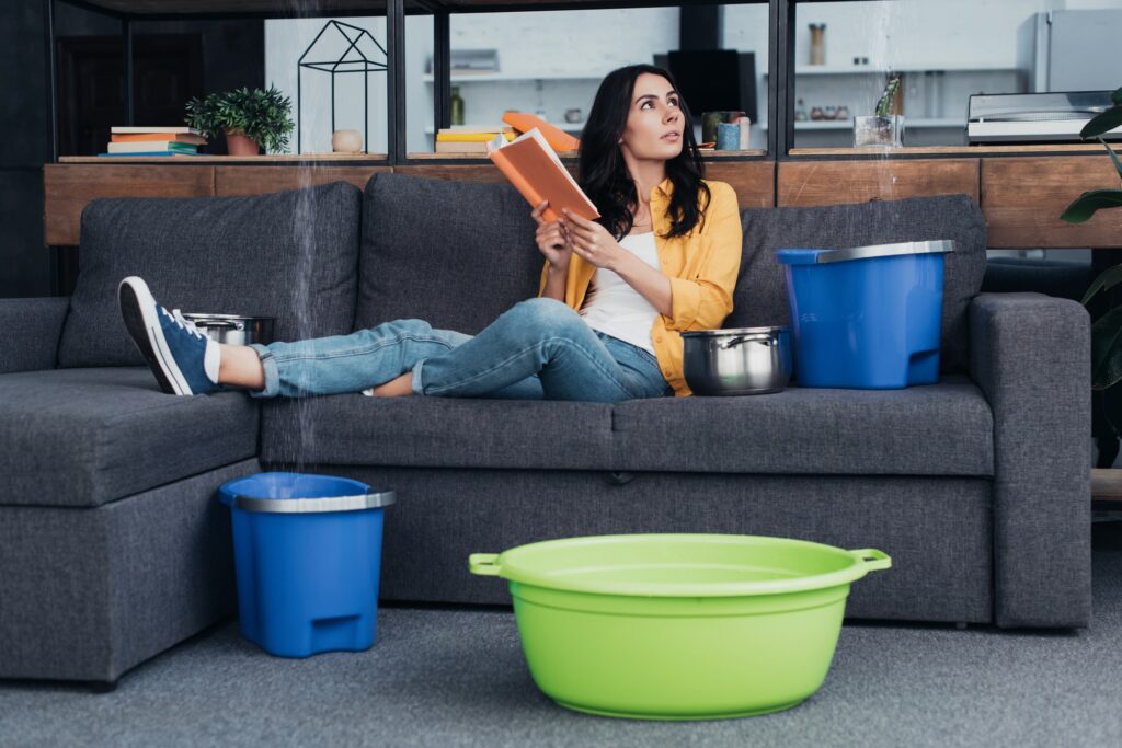 Woman reading book on sofa during water leak in living room
